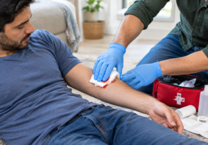A first aid helper applying firm direct pressure with gauze to control severe bleeding